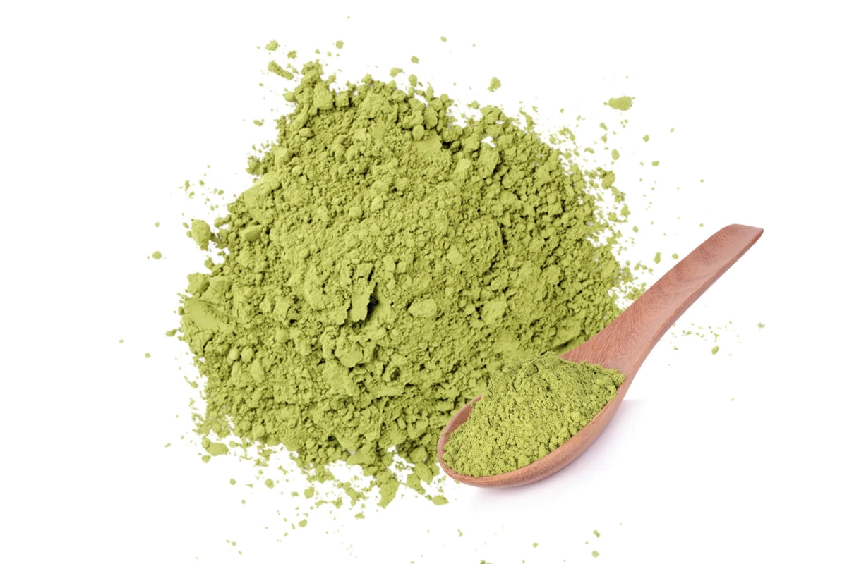 Green kratom powder pile with a wooden spoon